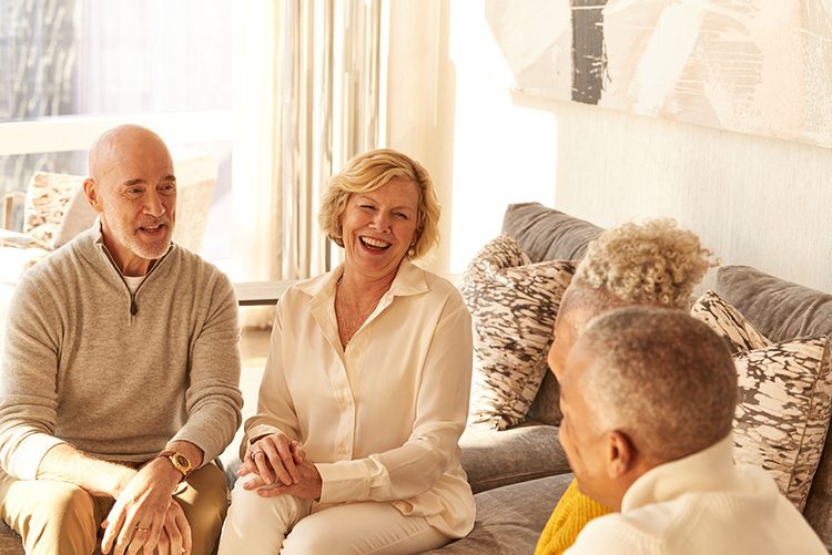 Senior couple sitting in living room with guests